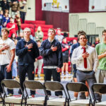 MVHS wrestlers and coaches standing together beside the mat.